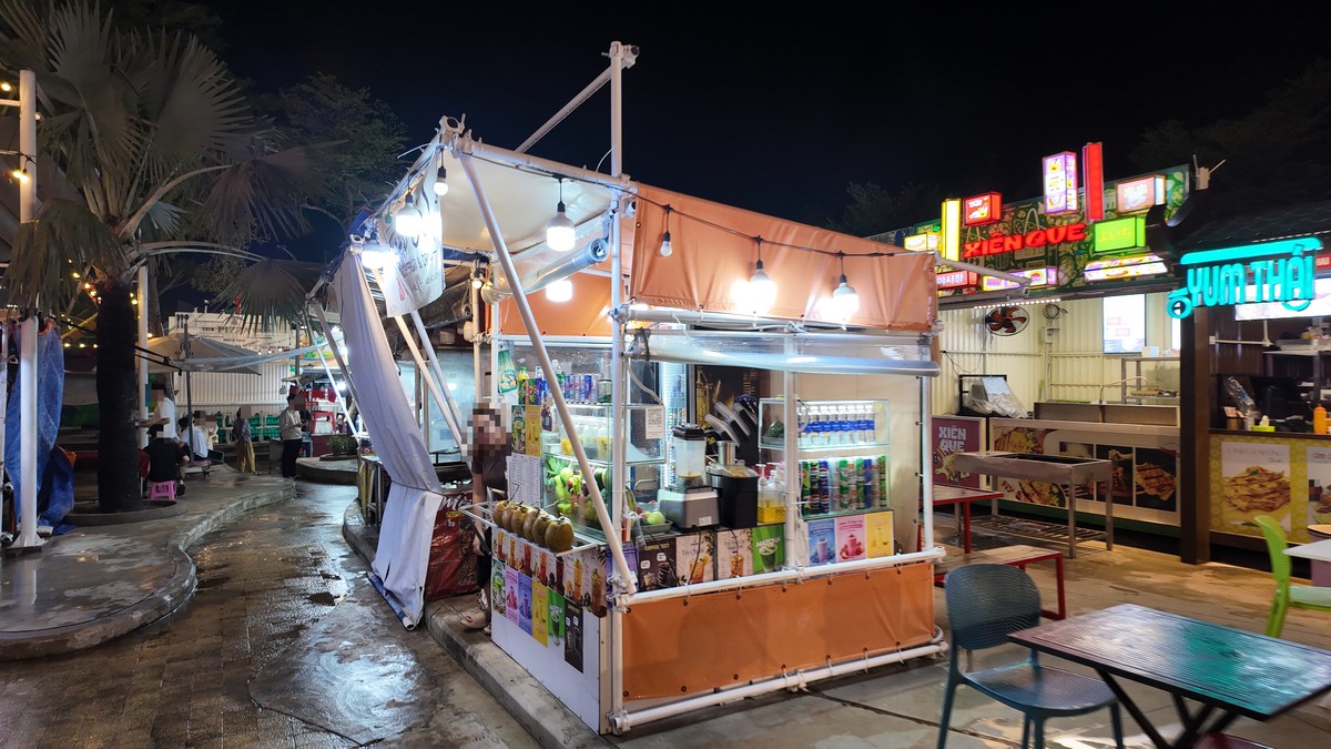 フルーツジュース屋台とYUM THAIのネオンが光る夜市