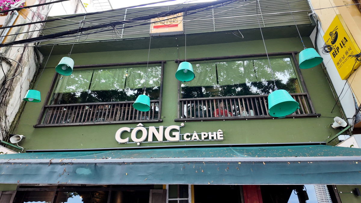 水色のランプと2階の窓が並ぶ「Cộng Cà Phê」の外観
